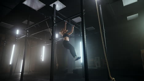 young-sporty-woman-is-hanging-on-crossbar-in-gym-and-doing-pull-up-hard-power-workout-in-fitness